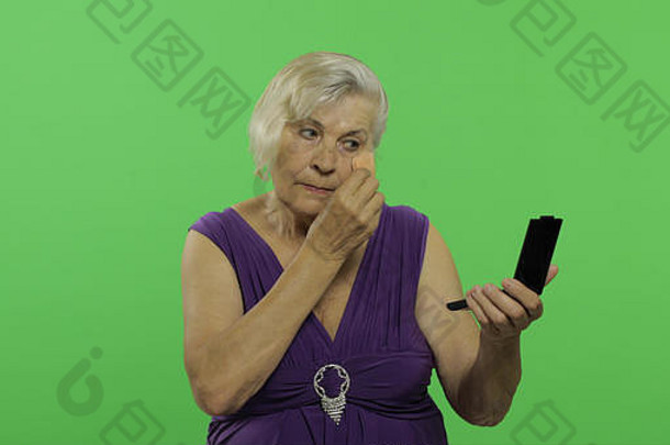上了年纪的女人使化妆漂亮的快乐祖母紫色的衣服的地方标志文本浓度关键绿色屏幕背景