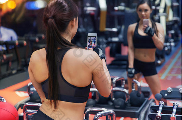 女人智能手机采取镜子自拍健身房