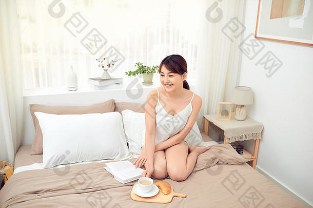 亚洲女人阅读书杯咖啡床上早....