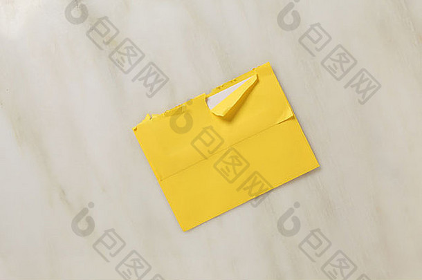 略撕裂开放邮政信封大理石表面明亮的黄色的彩色的信封