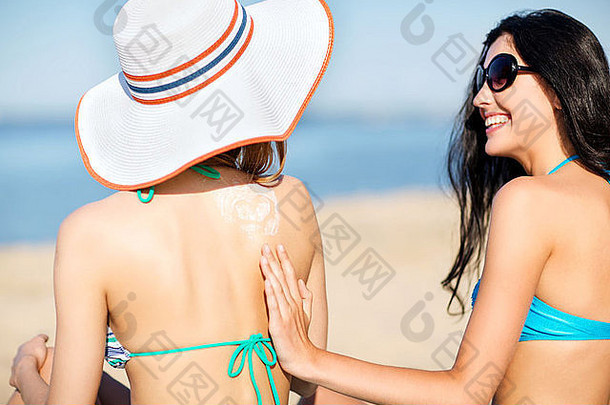女孩应用太阳奶油海滩