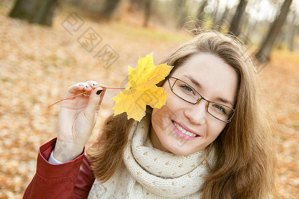美丽的年轻的女人秋天公园肖像持有秋天叶