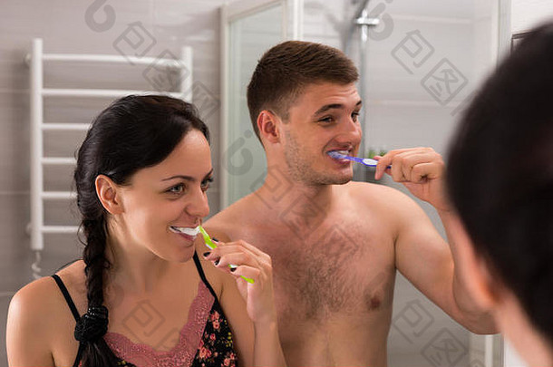 特写镜头快乐年轻的一对刷牙牙齿站前面镜子现代平铺的浴室首页