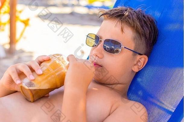 男孩太阳镜喝冰 沙咖啡稻草海滩希腊