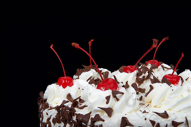 关闭前黑色的森林蛋糕孤立的黑暗背景生奶油剃巧克力糖果樱桃前