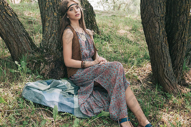 年轻的嬉皮女人坐着树森林