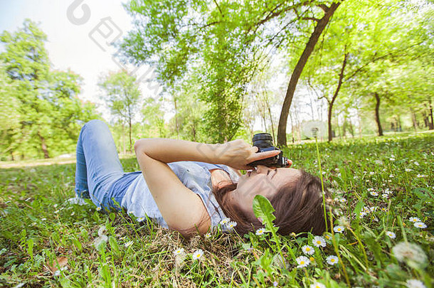 年轻的女人业余摄影师铺设地面采取照片古董相机自然