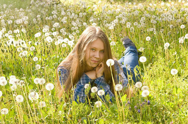 年轻的美丽的女孩十六岁欧洲长棕色（的）头发牛仔裤裙子铺设草地白色蒲公英