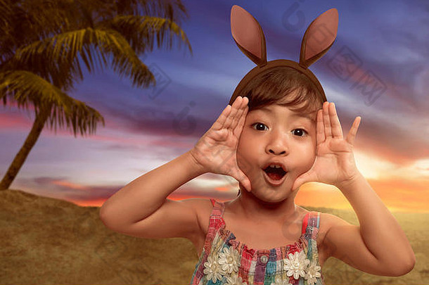可爱的亚洲女孩穿兔子耳朵复活节一天海滩