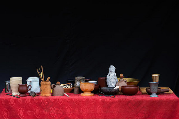很多粘土杯锅盘子花瓶菜前表格红色的桌布黑色的背景