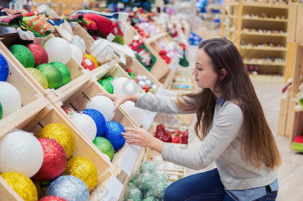 快乐的快乐客户女孩选择圣诞节树装饰球