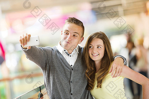 年轻的夫妇采取自拍手机购物购物中心