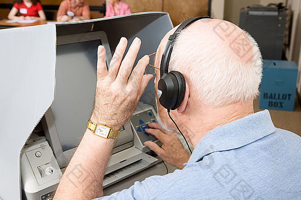 高级男人。触摸屏幕投票机装备听力愿景受损的选举工人可见背气