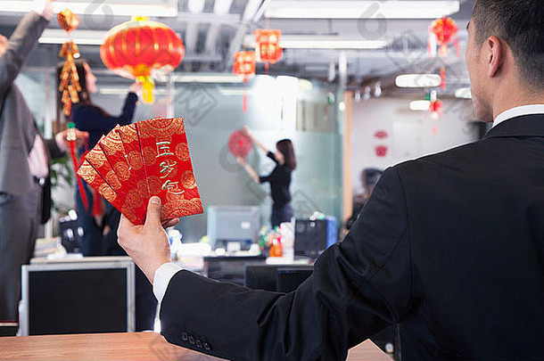 商人持有红色的信封同事挂装饰中国人一年