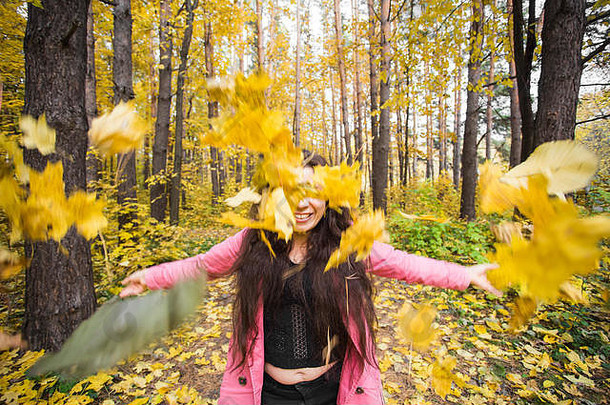 秋天快乐人概念年轻的女人有趣的秋天公园扔黄色的叶子天空