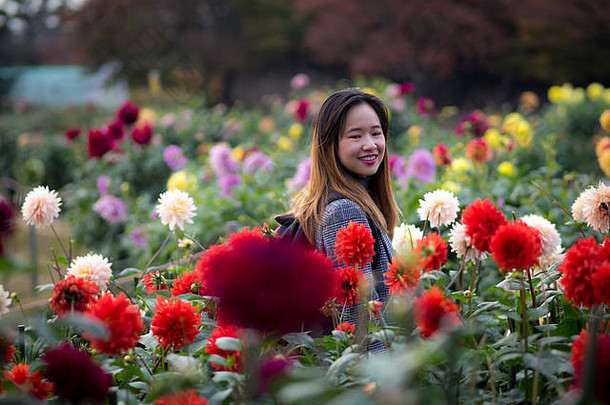 美丽的女人摆姿势红色的花日本花园