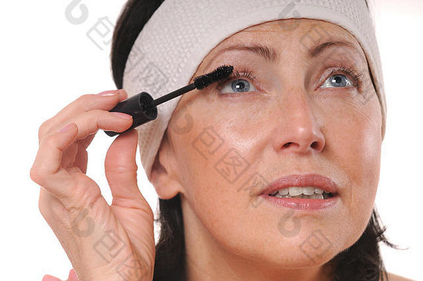 特写镜头肖像成熟的女人应用睫毛膏睫毛岁的女人把睫毛膏前面镜子