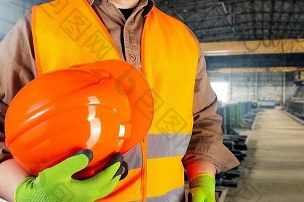 照片工人橙色夹克装手套持有保护orangle头盔躯干视图工<strong>厂区</strong>域背景