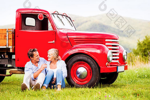 高级夫妇坐着红色的古董车