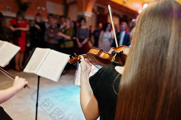 特写镜头肖像美丽的年轻的女小提琴家玩小提琴婚礼餐厅