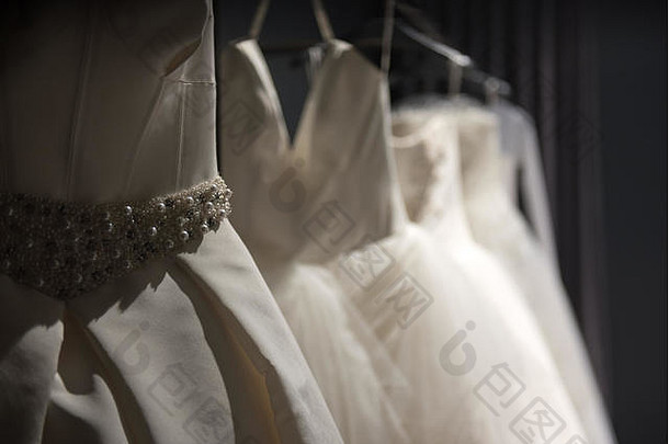 选择手工制作的白色婚礼礼服挂铁路黑暗的房间部分照亮光
