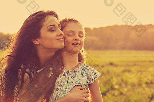 快乐享受妈妈。拥抱放松欢乐孩子女孩呼吸新鲜的空气日落明亮的夏天背景特写镜头健美的明亮的肖像