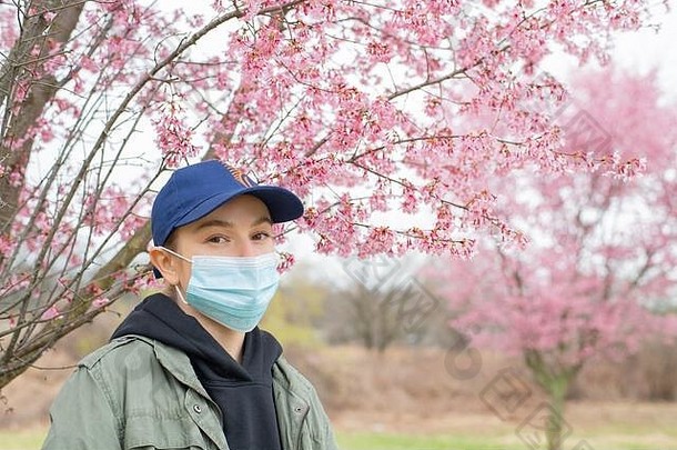 开始春天年轻的女人保护面具花粉过敏盛开的树公园