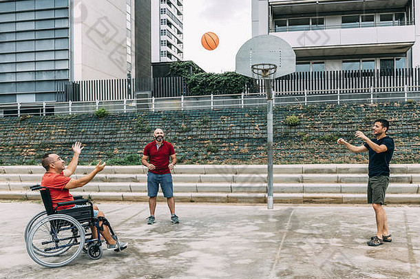 快乐的禁用男人。轮椅玩篮球朋友球概念自适应体育物理活动康复