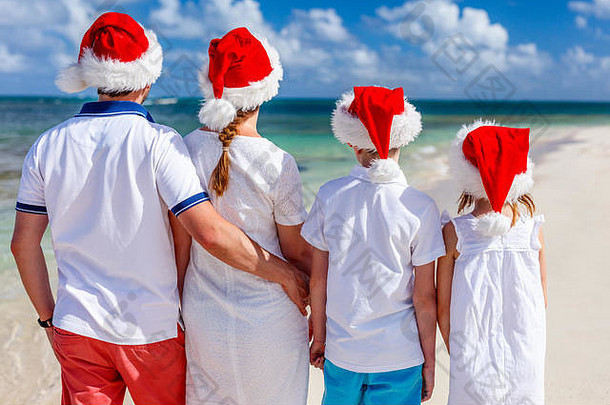 回来视图美丽的家庭穿红色的圣诞老人帽子热带海滩庆祝圣诞节