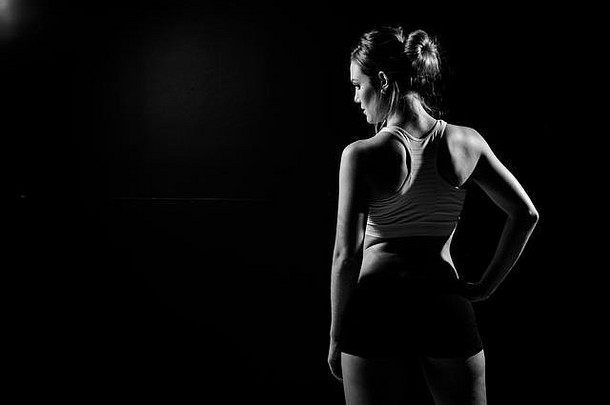 美丽的女健身模型持有毛巾权重黑暗工作室覆盖汗水培训