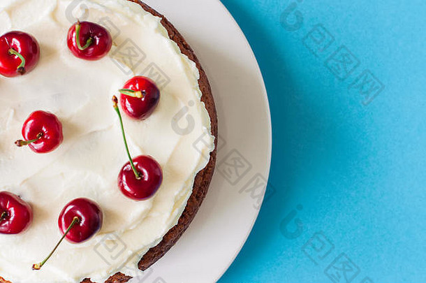 自制的酸奶油蛋糕奶油奶酪结霜装饰新鲜的成熟的樱桃光蓝色的背景