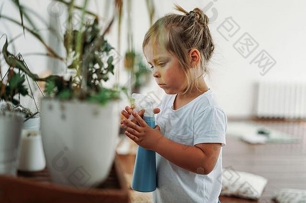 有趣的可爱的蹒跚学步的女孩浇水房子植物房间明亮的室内首页