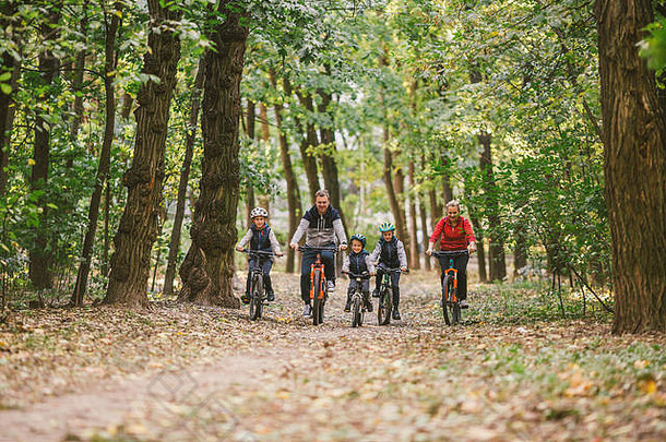 父母孩子们骑自行车森林小道年轻的家庭骑自行车秋天公园家庭山骑自行车森林主题家庭活跃的体育户外