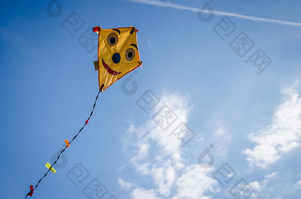 色彩斑斓的快乐微笑风筝飞行高蓝色的天空