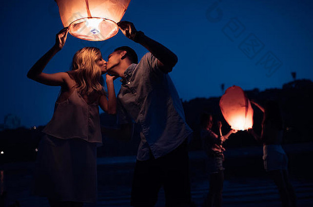 年轻的夫妇接吻持有天空<strong>灯笼</strong>河海滩晚上