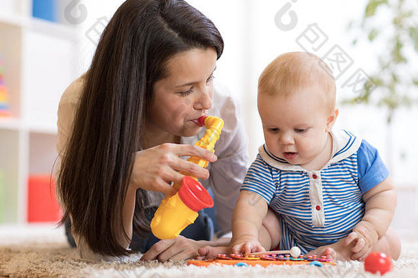 女人婴儿玩音乐的玩具托儿所