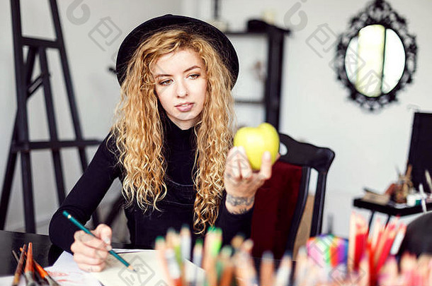 浪漫的金发女郎长头发卷曲的feemale艺术家黑色的他坐着表格颜色铅笔画绿色苹果