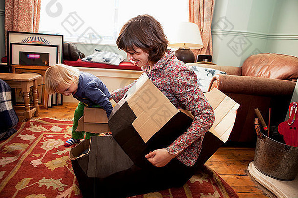 妈妈。儿子玩纸板盒子生活房间