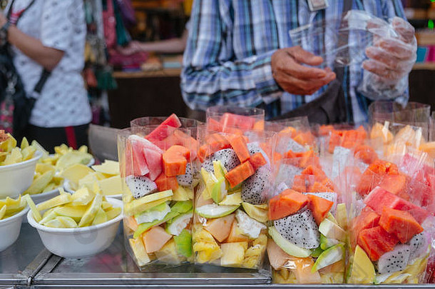 新鲜的热带水果塑料袋泡沫碗出售水果摊位当地的街食物市场曼谷泰国