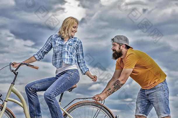 支持友谊女人游乐设施自行车天空背景服务援助男人。帮助平衡骑自行车女孩骑自行车男人。支持支持帮助