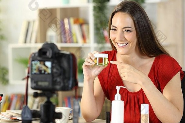 快乐美影响者女人显示化妆品产品记录视频相机坐着首页