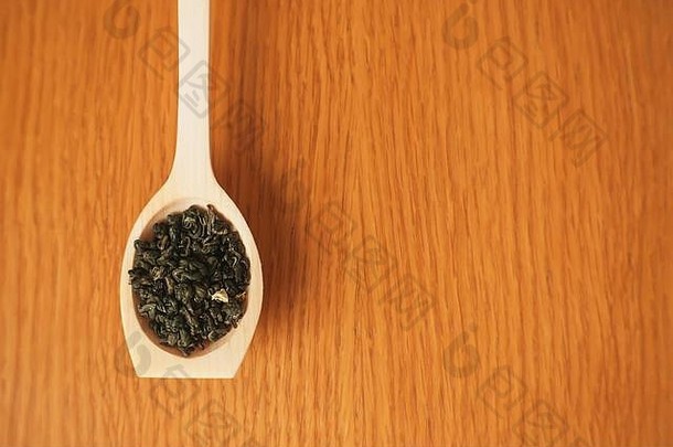木背景谎言手工制作的木勺子填满叶子香绿色茶