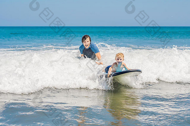 父亲教学年轻的儿子<strong>冲浪</strong>海假期假期旅行体育孩子们概念