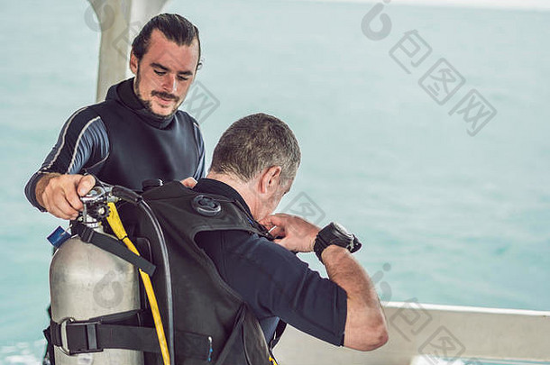 潜水教练帮助初学者潜水员准备潜水