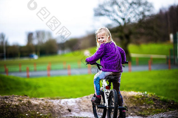 漂亮的女孩金发女郎头发紫色的跳投享受一天BMX跟踪骑练习技巧孩子农村