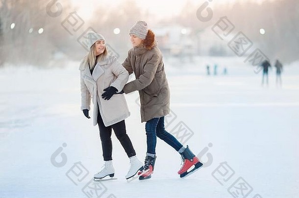 快乐年轻的爱夫妇持有手滑冰溜冰场雪冬天概念假期户外活动