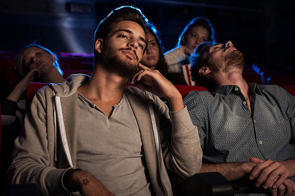 年轻的人看无聊的电影电影的家伙睡觉