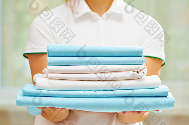 特写镜头女人的手持有堆栈清洁<strong>折叠床</strong>上表蓝色的白色颜色模糊背景