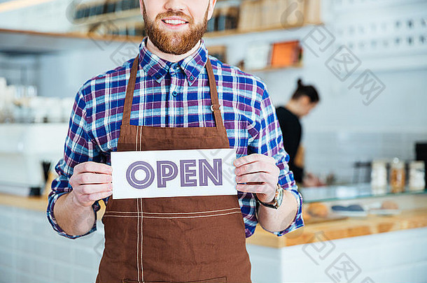 微笑有胡子的服务员棕色（的）围裙显示开放标志咖啡商店