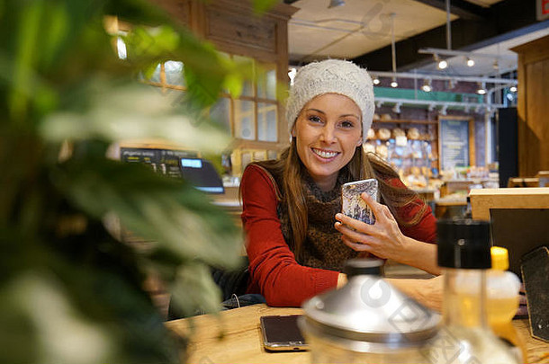 微笑年轻的女人连接智能手机咖啡商店